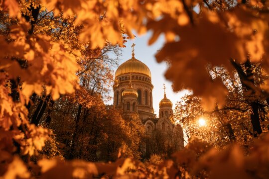 Orthodox cathedral with golden domes appearing through vibrant autumn foliage, illuminated by setting sun
