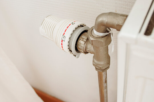 Close-up of a thermostatic radiator valve installed on a home heating radiator, manual control for adjusting room temperature.