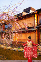 Young woman wearing traditional white and red Japanese kimonos in the Gion district of Kyoto – Gion District, Japan. © muratart