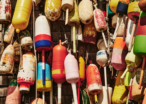weathered, colorful lobster buoys hanging against a rustic wooden shingle wall in Maine, New England