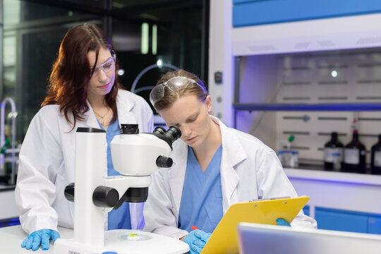 Scientist in lab coats engage in discussion in laboratory