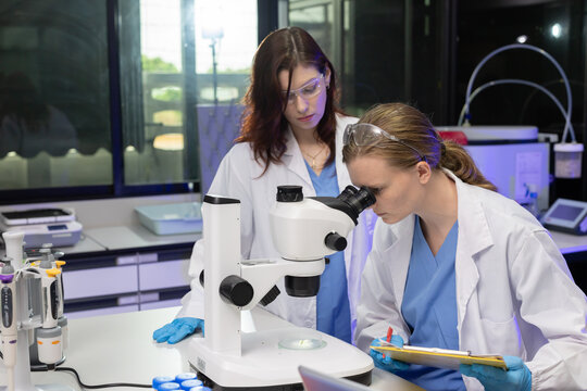 Scientist in lab coats engage in discussion in laboratory