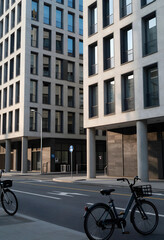 Obraz premium Urban mobility and sustainable city living, rental bicycles parked on a modern street with contemporary architecture and glass office building facade
