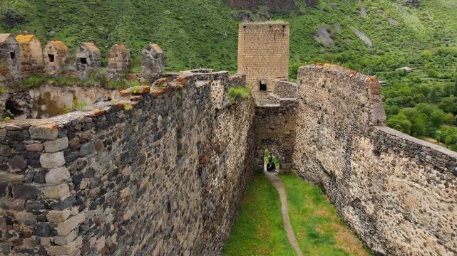 Khertvisi fortress, a medieval stone castle with towers and walls, standing on a high rocky hill in a lush green valley at the confluence of two rivers in southern georgia