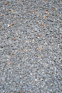 close up texture of small grey crushed stone gravel on ground outdoors