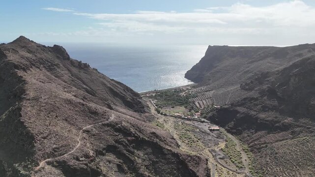 Panoramic aerial view of the remote El Cabrito hamlet in a deep valley leading to the ocean on La Gomera (Canary Islands). Features rugged cliffs and terraced fields near Roques Garc&iacute;a.