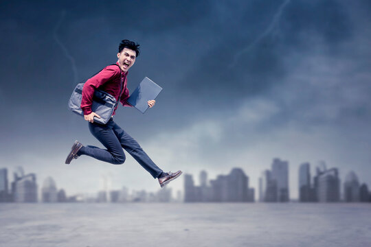 Panicked Businessman Running and Jumping Away from Stormy City Skyline with Laptop and Briefbag