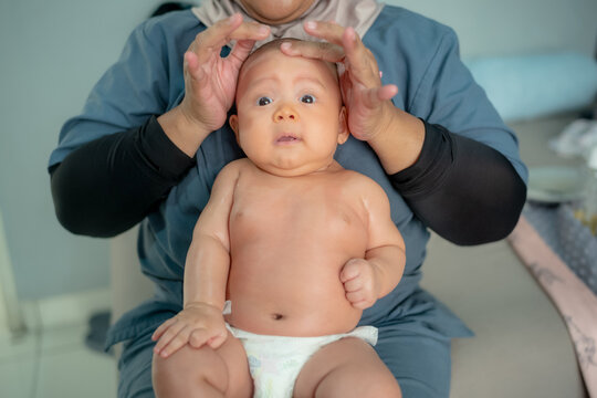 Asian Baby Receiving Head Massage from Therapist or Nurse in Baby Spa Treatment