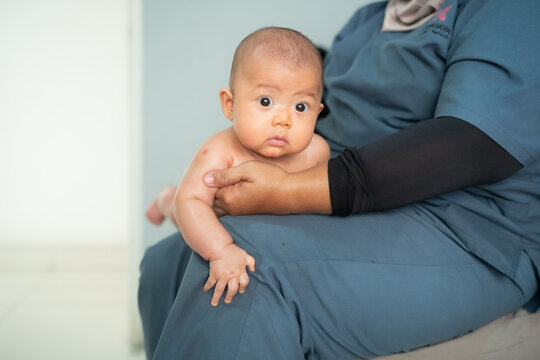 Asian Baby Held by Healthcare Worker or Therapist During Baby Massage or Physical Examination