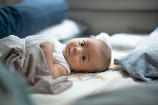 Adorable Baby Lying Comfortably on Bed Looking Direct at Camera