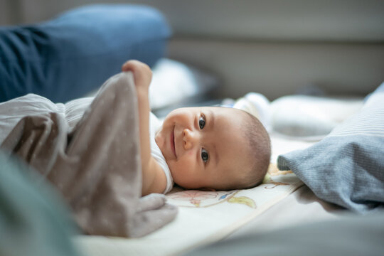Happy Smiling Baby Playing with Soft Blanket on Bed