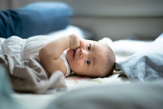Cute Baby Sucking Hand While Lying Comfortably on Bed