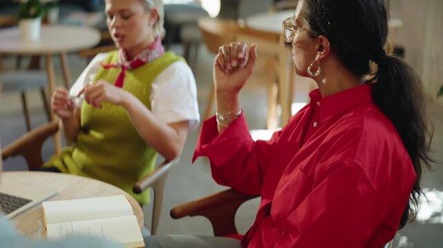 Woman and coworkers review notes during a team meeting at a cafe table, combining business collaboration, discussion, and coworking teamwork with planning in a casual workspace.