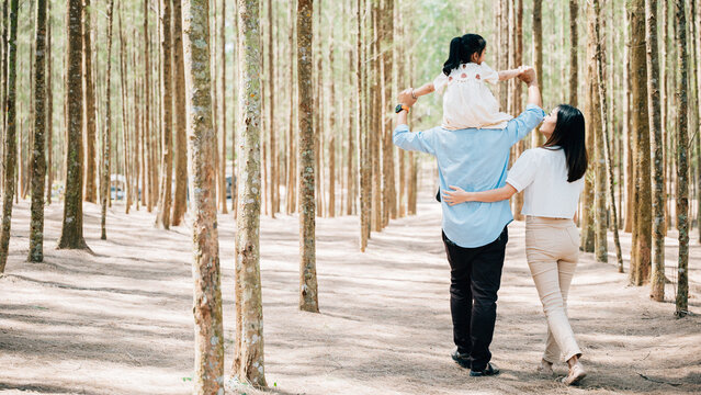 Family father carrying young girl shoulders while walking in forest with mother, Happy Asian family with adorable children in weekend, shoulder carry and happy family