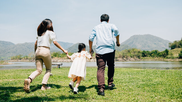 Asian family father mother and daughter holding hands and running lake in park, lifestyle parents and child kid enjoying outdoors together in nature on summer travel, Family relaxation