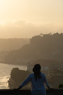 Person overlooking river cityscape in warm light