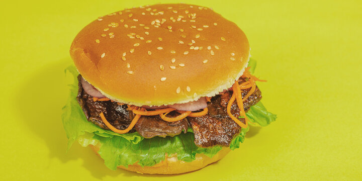 Vegan burger with grilled oyster mushrooms, carrot, red onion, and lettuce in a sesame bun