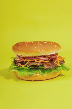 Vegan burger with grilled oyster mushrooms, carrot, red onion, and lettuce in a sesame bun
