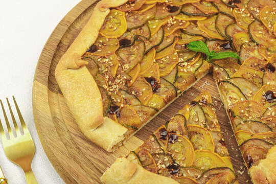 Baked rustic zucchini galette slices on garnished with fresh basil. Homemade savory vegetable tart