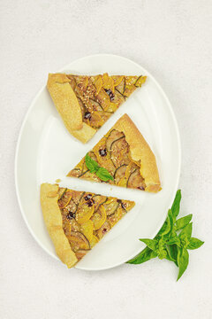 Baked rustic zucchini galette slices on garnished with fresh basil. Homemade savory vegetable tart