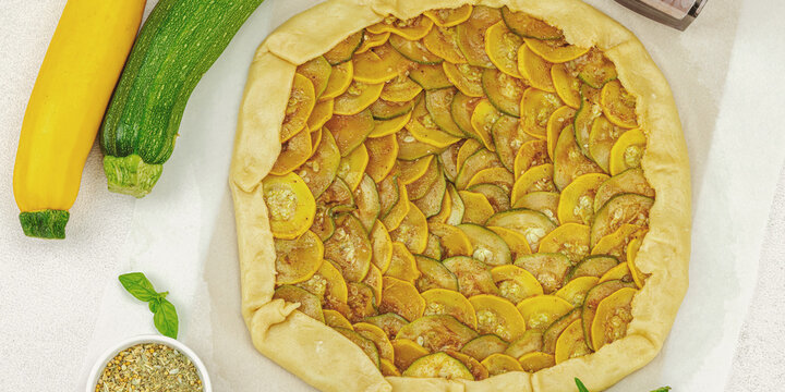 Preparation of rustic zucchini galette with two varieties of squash arranged on parchment paper