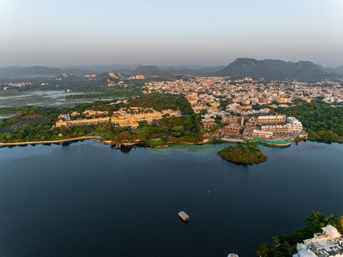 Aerial view of the historic City Palace and lush gardens along the shores of Lake Pichola in Udaipur, Rajasthan, India.