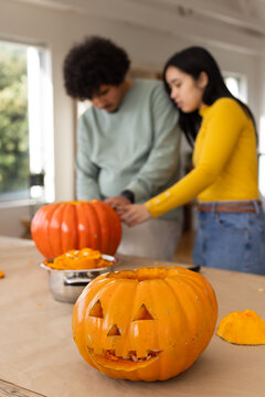African American couple carving pumpkins at home with carved pumpkin, metal bowl, pulp halloween