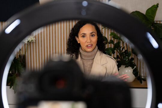 African American woman speaking to camera in home studio, gesturing at DSLR, ring light halo