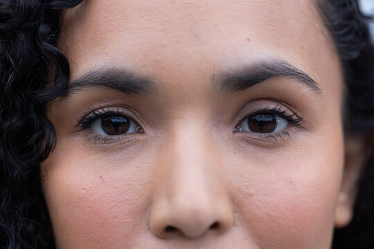 African American woman looking at camera, showing eyes, skin texture and curly hair in studio