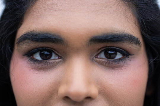 Adult female gazing into camera in studio, showcasing eyeliner mascara and subtle cheek blush