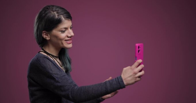 Young woman takes a selfie with an abstract pose against a purple background