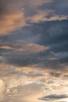 View of dramatic storm clouds at sunset over the Sacred Valley with golden light illuminating the dark sky in Urubamba Province, Cusco, Peru.