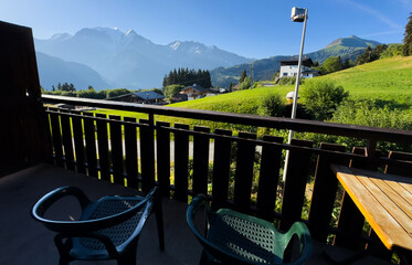 Obraz premium cozy wooden balcony with comfortable lounge chair overlooking scenic green mountains