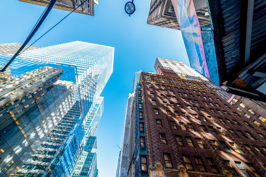 Historic and modern Manhattan skyscrapers viewed from below under a blue sky