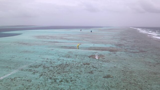 Aerial view of kitesurfing over the turquoise waters of the Los Roques archipelago with colorful kites and riders in Los Roques, Dependencias Federales, Venezuela.