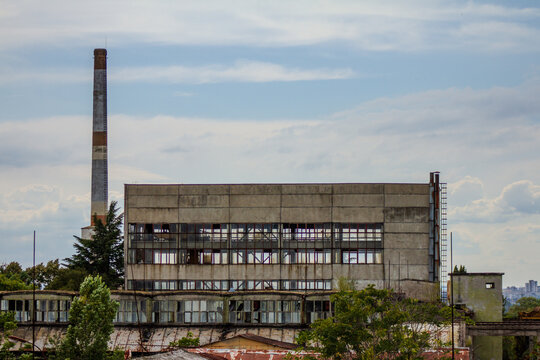 Abandoned industrial factory building with tall smokestack chimney background