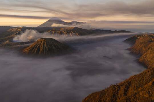 Volcanic peaks rise above a blanket of mist at sunrise near Mount Bromo in East Java, Indonesia.