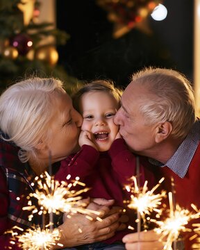 Happy grandparents kiss their laughing grandchild beside glowing sparklers at Christmas, warm intergenerational family concept for holiday reunion, affection and shared memories