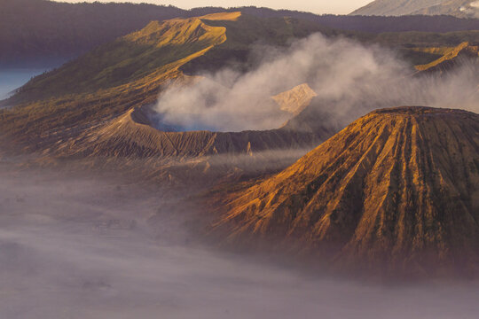 Volcanic peaks rise above a blanket of mist at sunrise near Mount Bromo in East Java, Indonesia.