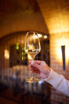 Close-up of a Hand Holding a Wine Glass in an Antique Brick Cellar