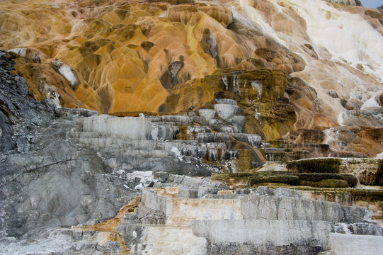View of the colorful travertine terraces at Mammoth Hot Springs with mineral deposits and layered rock formations in Yellowstone National Park, United States.