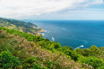 Obraz premium Green hills and rocky coastline of Cantabrian Sea in San Sebastian, Basque Country, Spain. Euskadi natural landscape for Atlantic travel, coastal tourism, outdoor vacations, scenic routes