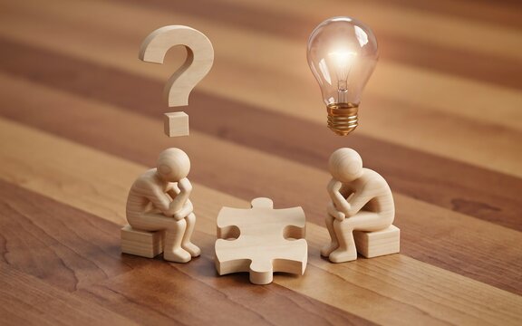 Wooden figurines sitting with puzzle piece question mark and glowing lightbulb symbol representing problem solving and creative thinking in business development.