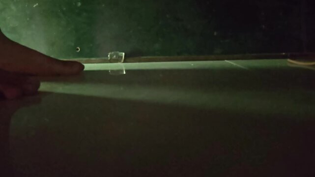 A person's hand enters the frame to pick up the discarded paper