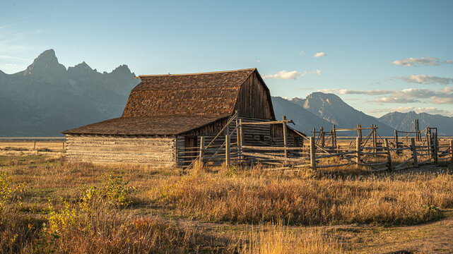 View of the historic Moulton Barn in Jackson Hole with the Teton mountain range in the background under golden hour light in Teton County, Wyoming, United States.