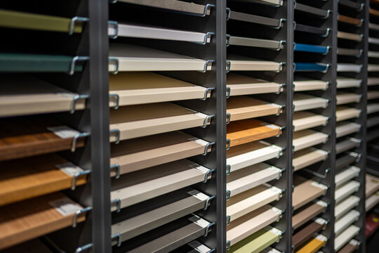 Furniture panel samples in different colors and finishes displayed on showroom racks. Shallow depth of field and selective focus create blurred background with copy space