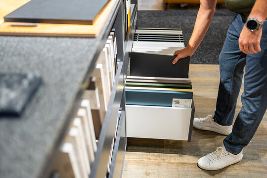 Man browses cabinet door samples in furniture showroom. Choosing colors and finishes for kitchen renovation with selective focus and soft background