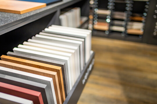 Cabinet door samples in different colors and wood finishes are displayed in furniture showroom. Material selection for kitchen design with selective focus and soft background