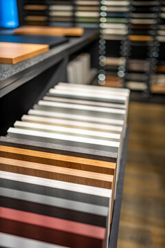 Cabinet door samples in different colors and wood finishes are displayed in furniture showroom. Material selection for kitchen design with selective focus and soft background