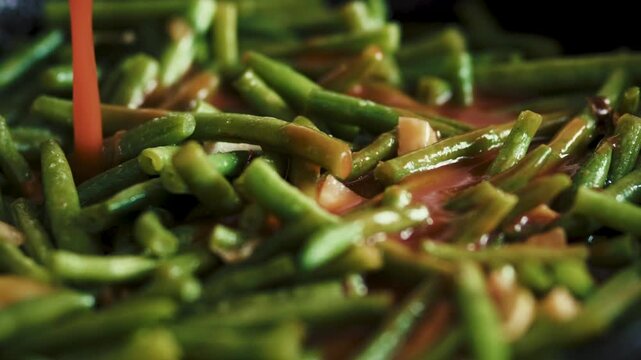 Delicious green beans boiling in tomato sauce on a frying pan